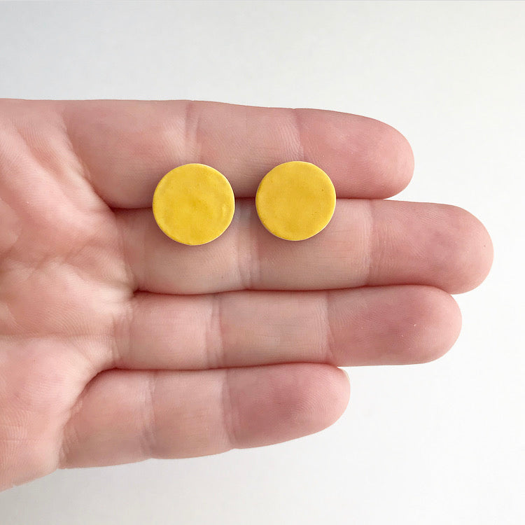 Circle, ceramic stud earrings with yellow glaze.