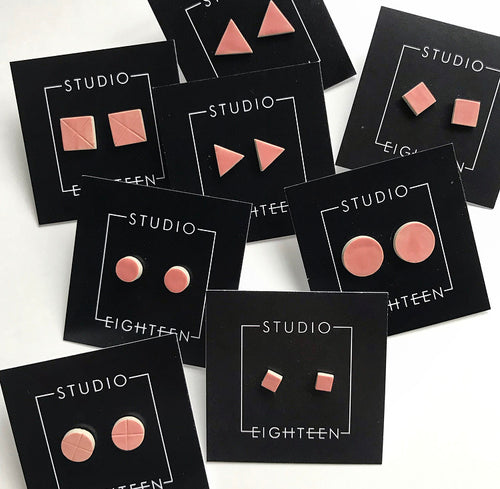 A variety of geometric shaped ceramic stud earrings with pink glaze